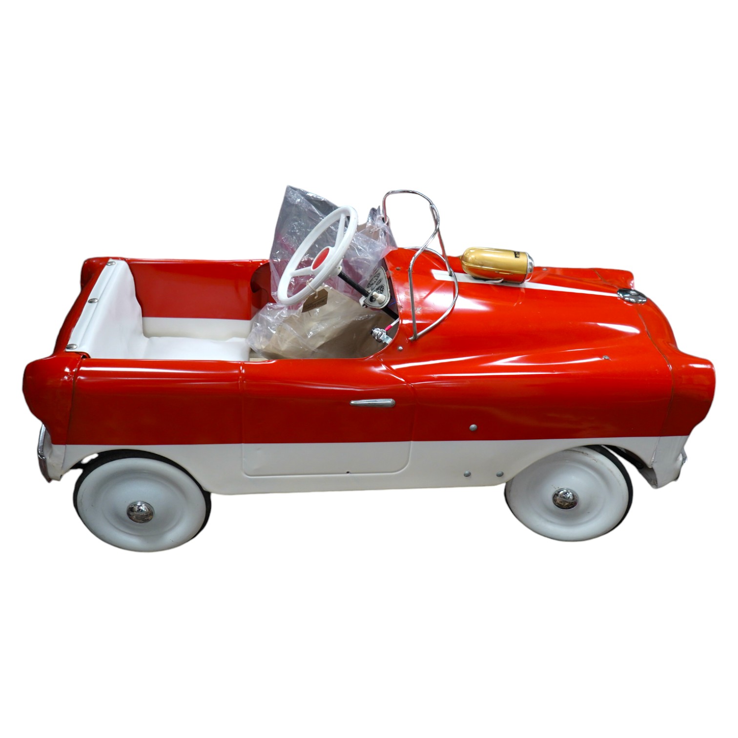 A tinplate Tri-ang T65 pedal car, based on a Ford Zephyr, with vinyl padded seat, working steering, working electric headlights, original paperwork and Radar bicycle horn with original card box, length 98cm. Condition -